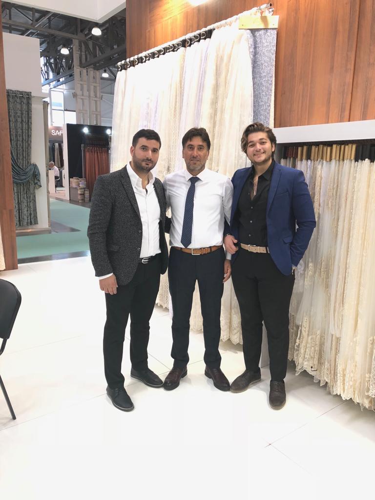 Cuma, his brother, and his son standing next to each other in a textile tradeshow in Russia